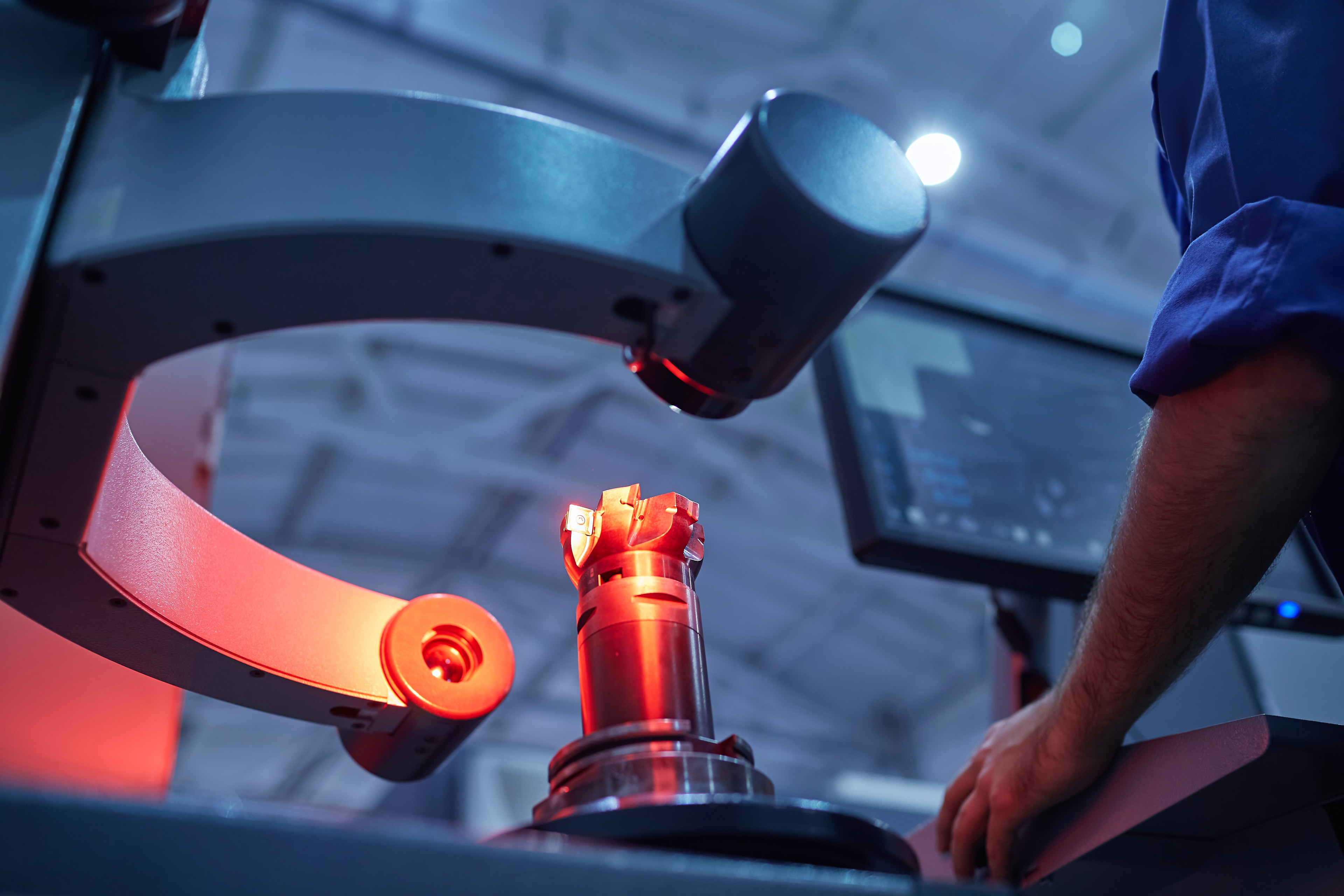 An engineer checking a machined part under an optical mea ring system